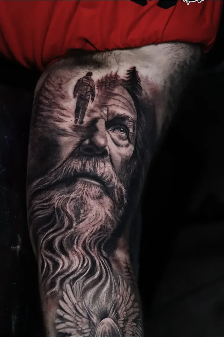 Black and grey double-exposure tattoo of a face merged with a landscape